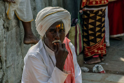 Senior man in turban sitting outdoors at market