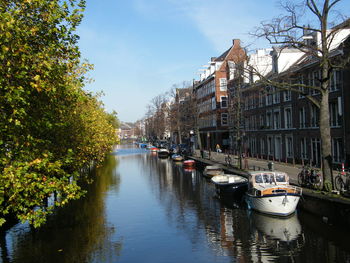 Boats moored in canal amidst buildings in city