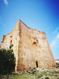 Low angle view of old building against blue sky