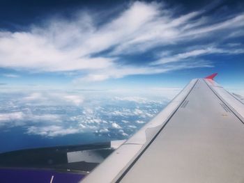 Cropped image of airplane flying over sea against sky