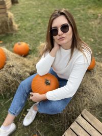 Portrait of young woman wearing sunglasses while sitting on field