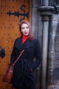 Portrait of woman standing against door