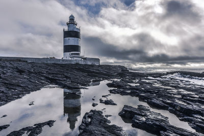 Lighthouse by sea against sky during winter