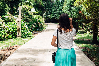 Rear view of woman walking on footpath at park