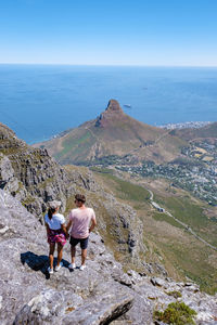 Rear view of man walking on mountain against sky