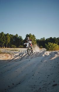 Man riding bicycle on road against clear sky