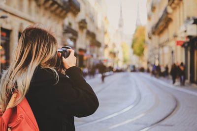 Rear view of woman photographing on street