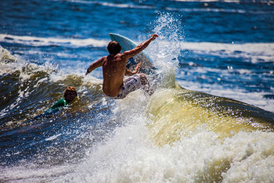 Shirtless man surfing in sea on sunny day