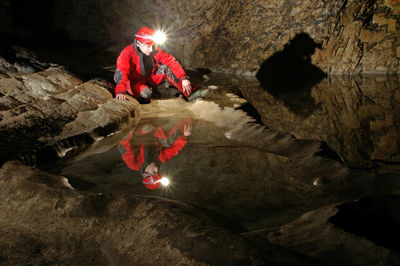 Reflection of a spelunker in a cave water pool. carbide acetylene gas lamp on helmet 