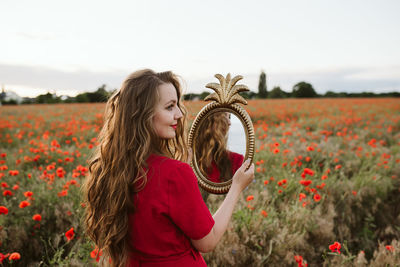 Young woman holding a mirror in a field