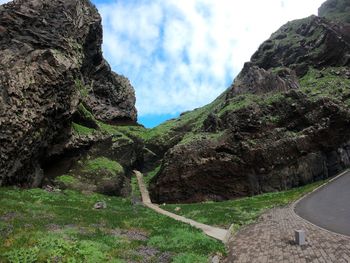 Road amidst green mountains against sky