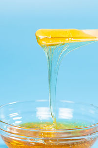 Close-up of yellow glass against blue background