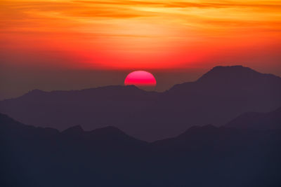 Scenic view of silhouette mountains against romantic sky at sunset