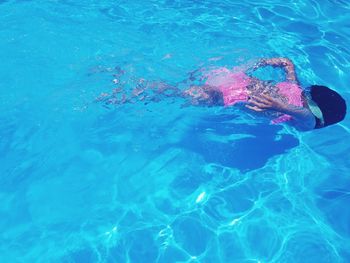 High angle view of child swimming in pool on sunny day