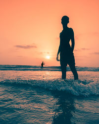 Silhouette men on beach against sky during sunset
