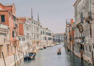 Boats in canal amidst buildings against clear sky