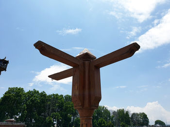 Low angle view of cross amidst trees against sky