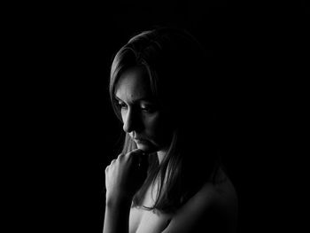 Close-up portrait of a young woman over black background