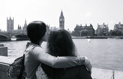 Mother and daughter by thames river against big ben on sunny day