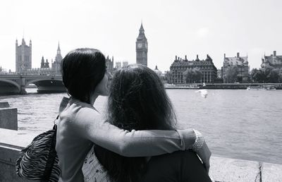 Rear view of man and woman looking at river with city in background