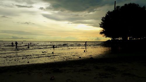 Silhouette people on beach against sky during sunset