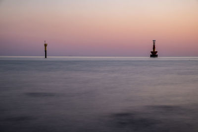 Lighthouse by sea against sky during sunset