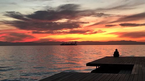 Silhouette pier over sea against sky during sunset