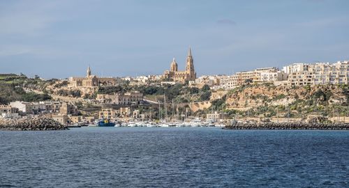 View of city by sea against sky