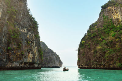 Landscape of a ship sailing between two rocks with vegetation. blue.