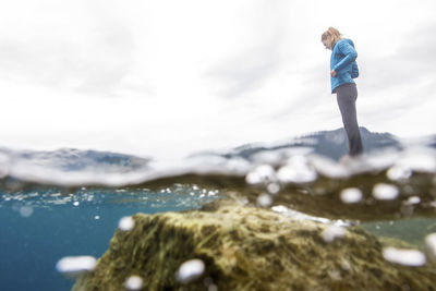 Low angle view of thoughtful woman by lake against sky