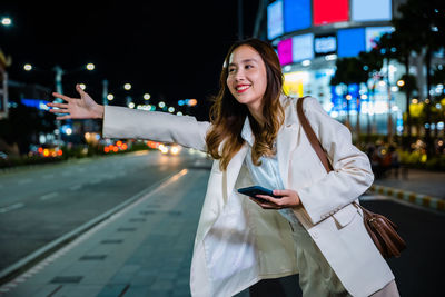 Portrait of young woman standing in city at night