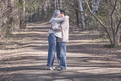 Full length of man and woman standing in forest