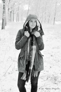 Smiling young woman standing in snowy field