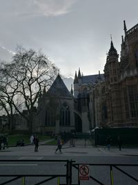 People walking on street by buildings against sky in city