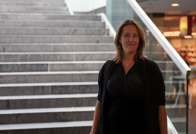 Portrait of woman standing against staircase