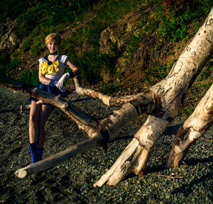 Full length of man sitting on tree trunk