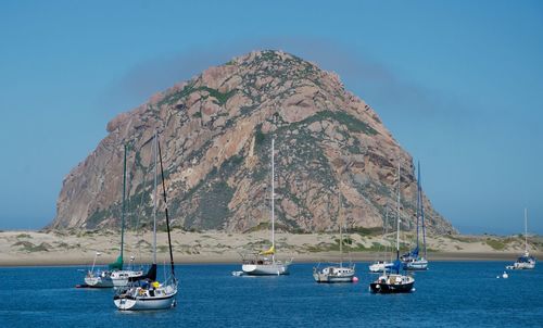 Boats in sea against mountain