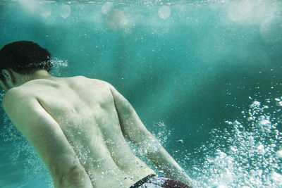 Rear view of man swimming underwater