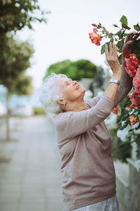 Elderly woman admiring beautiful bushes with colorful roses
