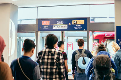 Rear view of people standing at railroad station