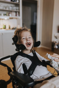 Happy disabled girl in wheelchair looking at camera