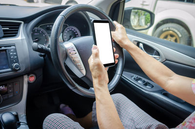 Midsection of man using smart phone in car