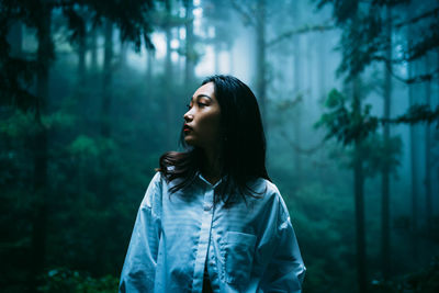 Young woman looking away in forest