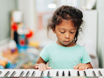 Cute girl playing piano at home