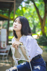 Woman looking away while sitting outdoors