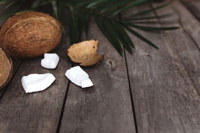 Broken coconuts on gray wooden background with palm leaf. white coconut pulp. high quality photo