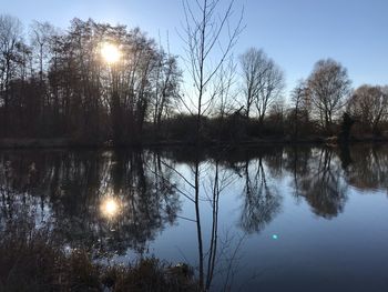 Reflection of silhouette trees in lake against sky