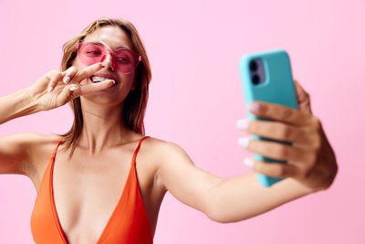 Young woman holding mobile phone against white background