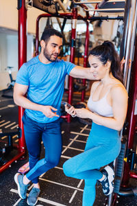 Full length of man and woman standing in gym taking a break from exercising 