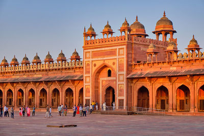 Group of people in front of historic building against clear sky